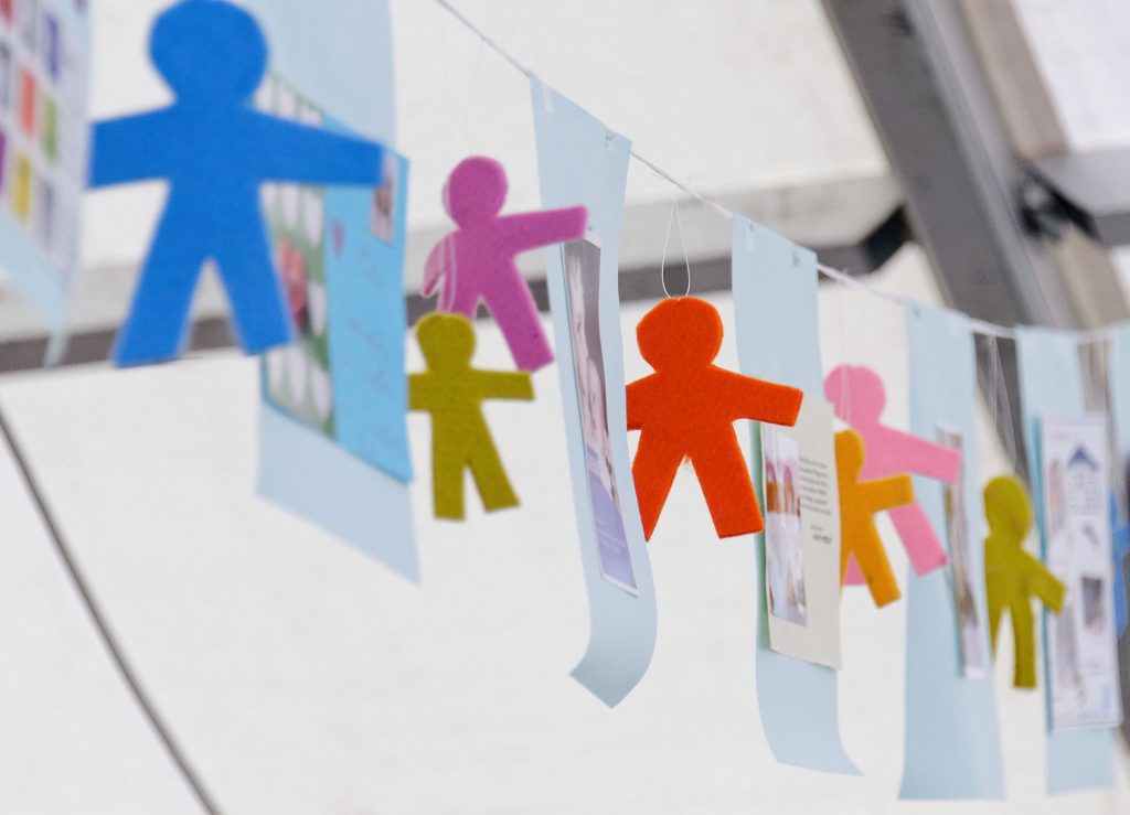 Filzfiguren in verschiedene Farben und Größen hängen zwischen Zetteln mit Nachrichten von Kindern des bunten Kreises.