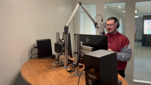 Männliche Person steht in Aufnahmestudio und spricht in Mikrophone